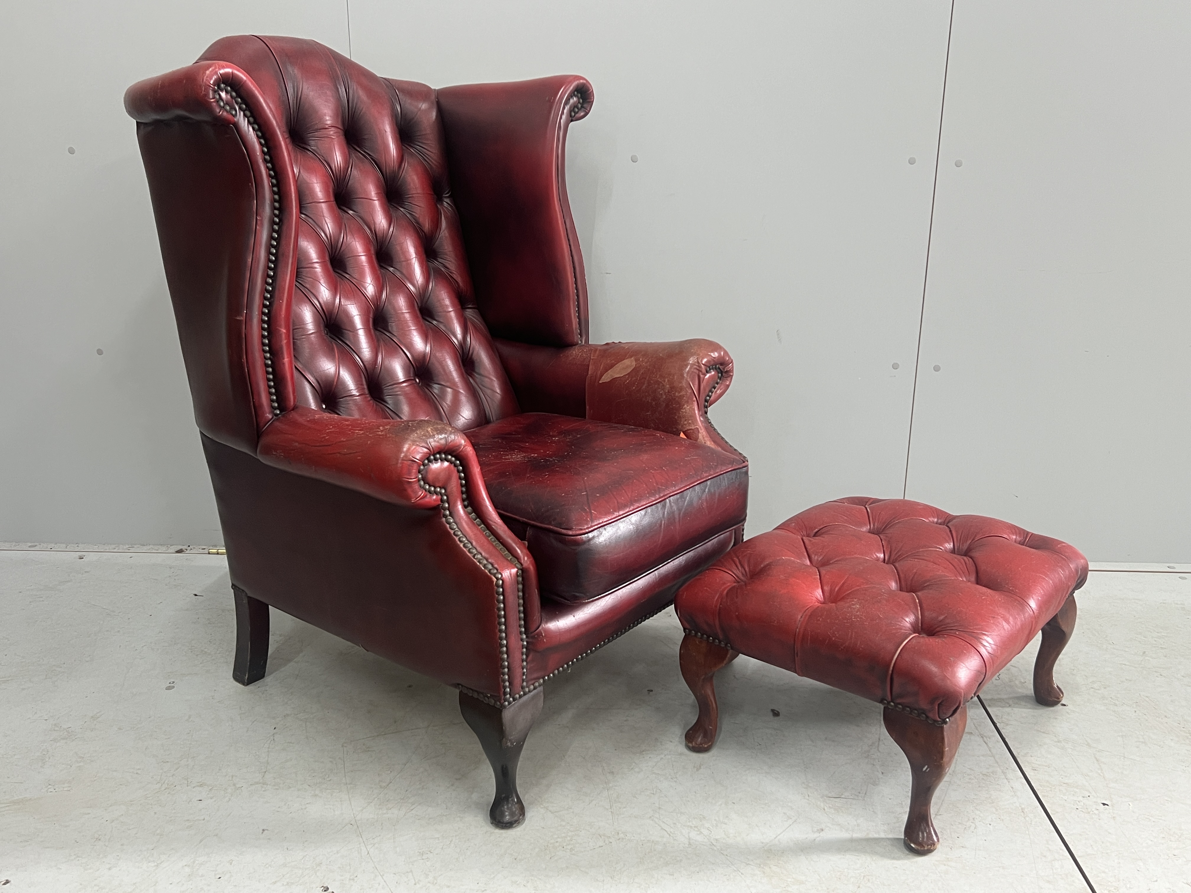 A Victorian style leather armchair, width 82cm, depth 80cm, height 110cm and footstool